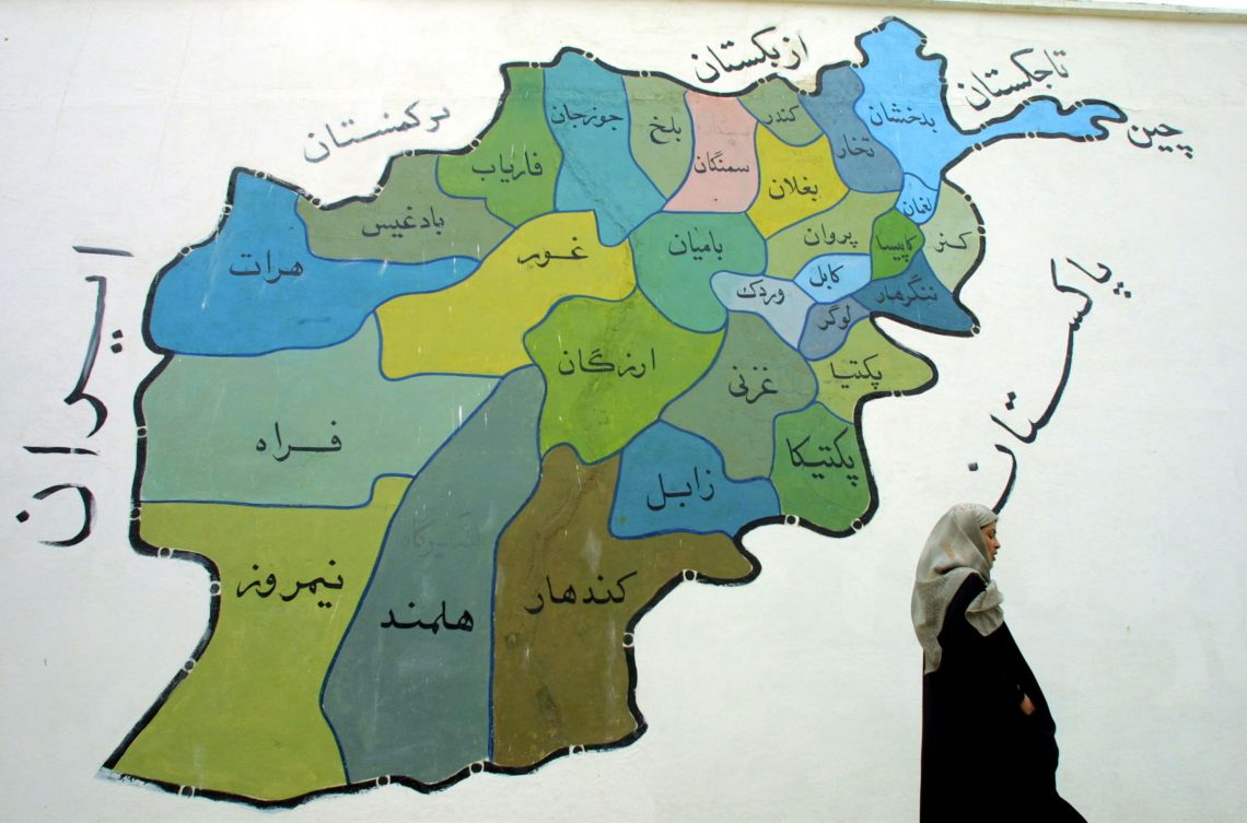 Eine Delegierte der Großen Ratsversammlung in Afghanistan geht an einem Wandbild des Landes vorbei