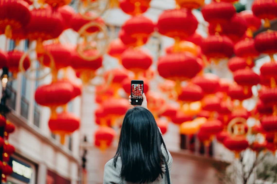 Frau mit Handy vor chinesischen Laternen