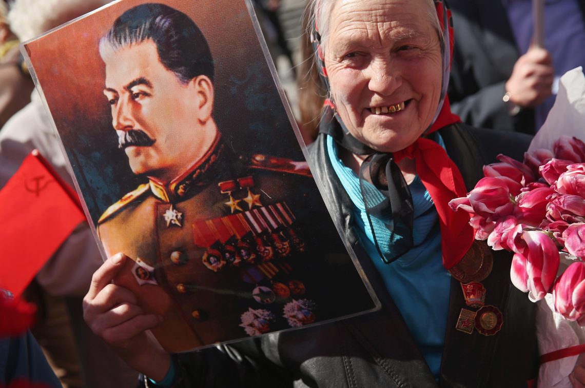 Eine Pensionistin hält auf einem Gedenkmarsch für den Zweiten Weltkrieg ein Porträt Stalins