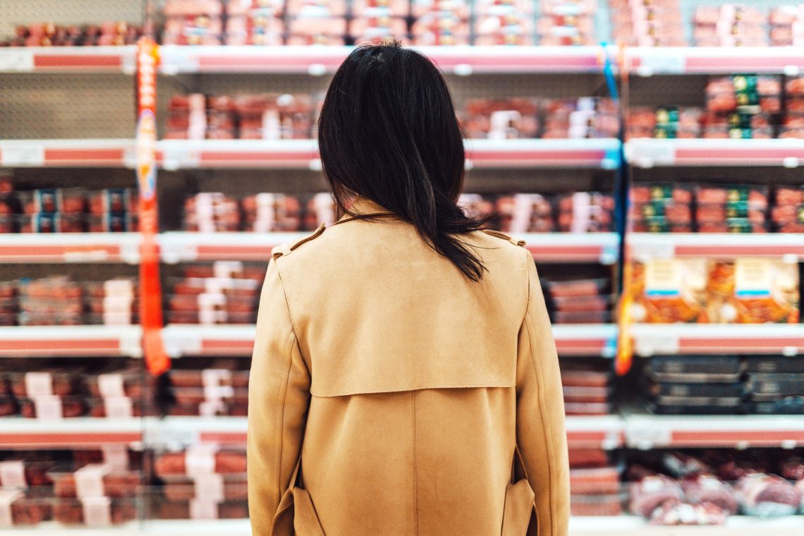 Frau steht vor einem Fleischregal im Supermarkt