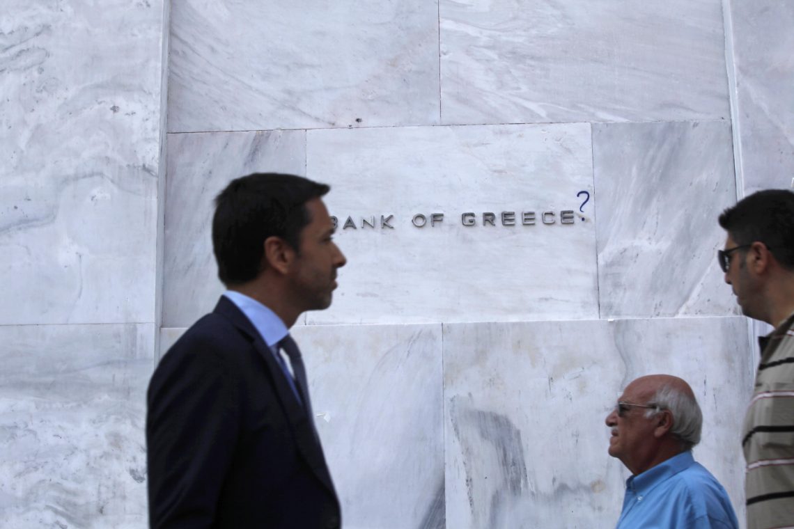 Passanten vor der griechischen Zentralbank, deren Logo mit einem Graffiti verunstaltet wurde