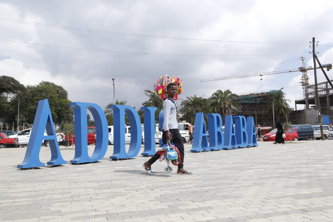 Foto eines jungen Mannes, der an dem Schriftzug Addis Abeba vorbei über einen Platz geht.