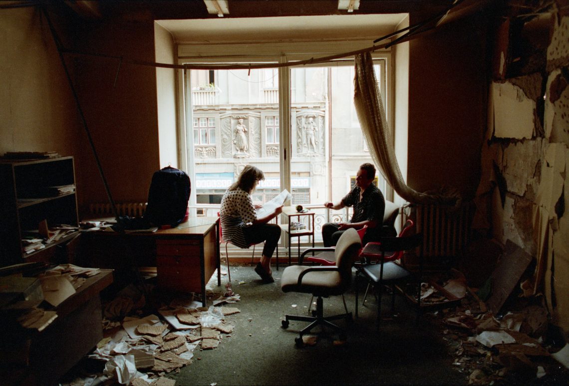 Ein Paar liest Zeitung in einer von Granaten beschädigten Wohnung in Sarajevo