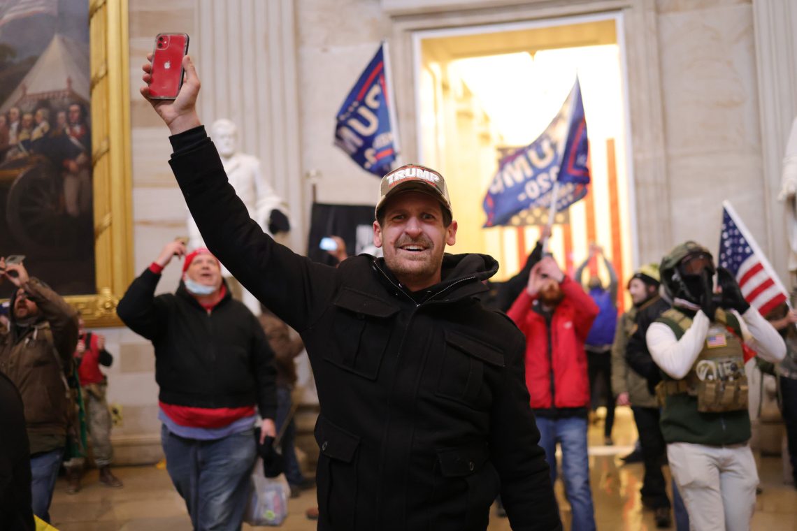 Ein Demonstrant beim Sturm auf das US-Kapitol, der ein Handy in die Höhe hält