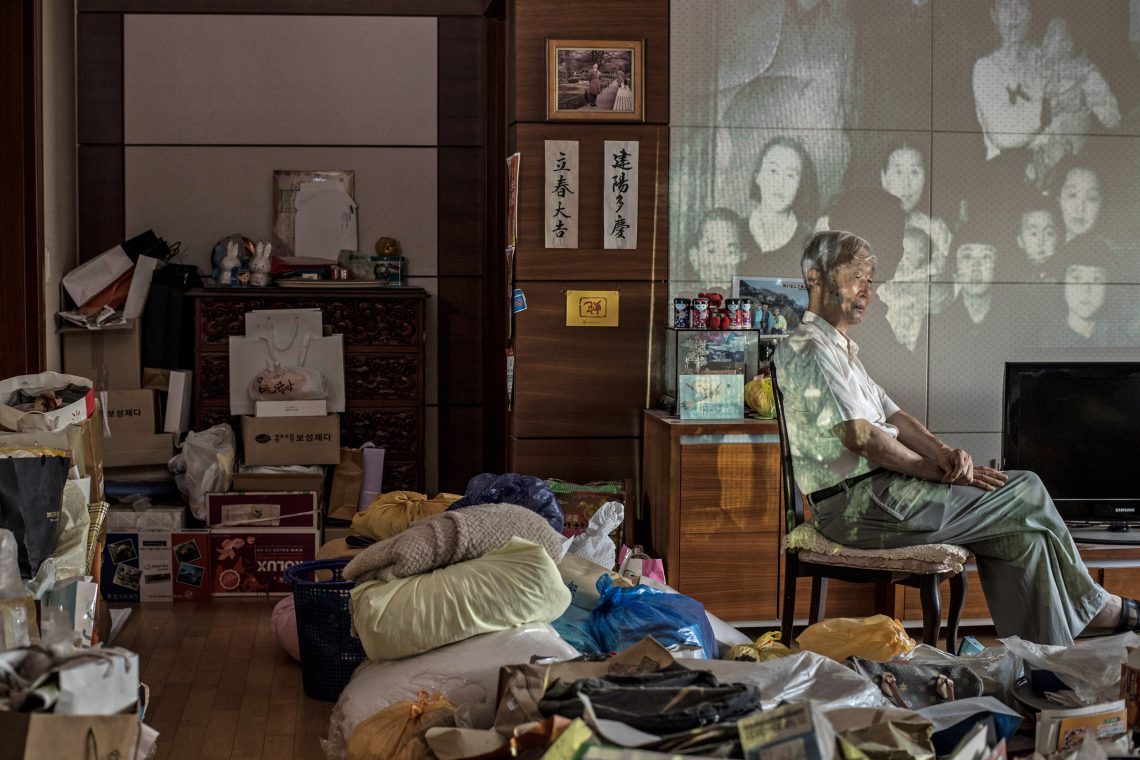 Älterer Mann in Südkorea sitzt vor einer Projektion von Fotos seiner nordkoreanischen Familie