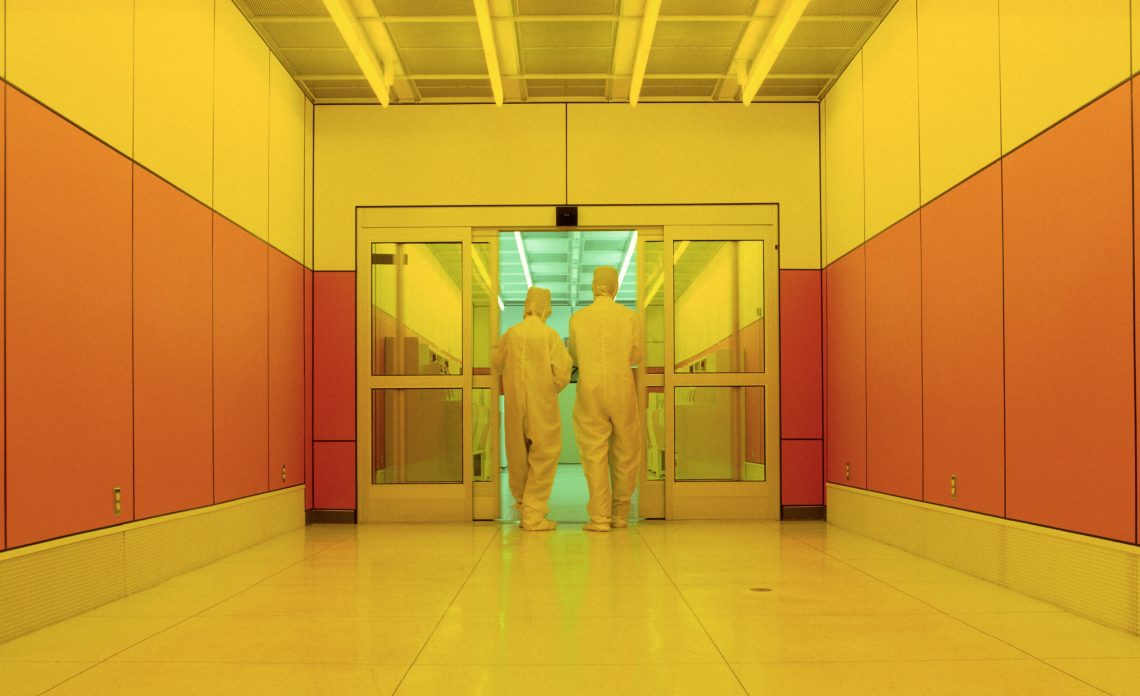 Silicon Valley auf der Suche nach Unsterblichkeit. Tech-Mitarbeiter in Schutzanzügen in einer gelb beleuchteten Halle.