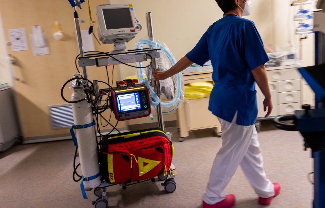 Folgen einer Cyberattacke: Foto einer Krankenschwester, die ein Beatmungsgerät auf einem Rollwagen zieht.