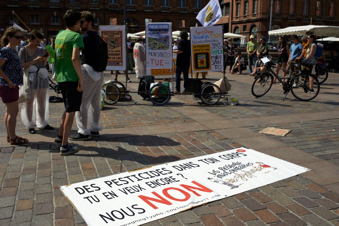 Foto von Gentechnik-Protesten in Frankreich mit einem Plakat gegen Pestizide.