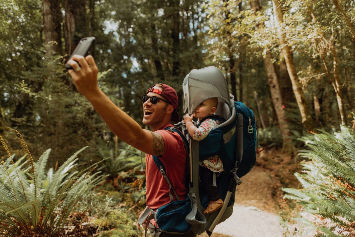 Vater mit Baby macht Selfie im Wald, Queenstown, Neuseeland