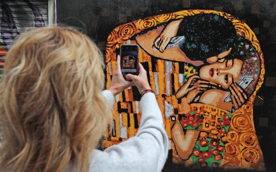 Eine Touristin fotografiert das Straßenkunstwerk des irischen Künstlers ADW im Stadtzentrum von Dublin. Das Bild, das auf dem "Kuss" von Gustav Klimt basiert, verdeutlicht das Übel der Handysucht.