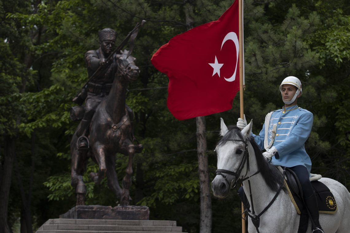 Foto einer Parade der türkischen Kavallerie. Ein Reiter auf einem weißen Pferd trägt eine türkische Fahne.
