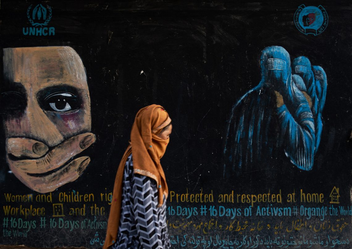 Frauenrechte: Eine mit einem Schal verhüllte Frau geht an einer Mauer mit einer Wandmalerei vorbei.