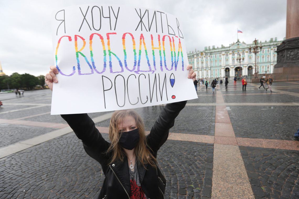 Eine Frau hält auf einem Platz ein Plakat in russischer Sprache in die Höhe.
