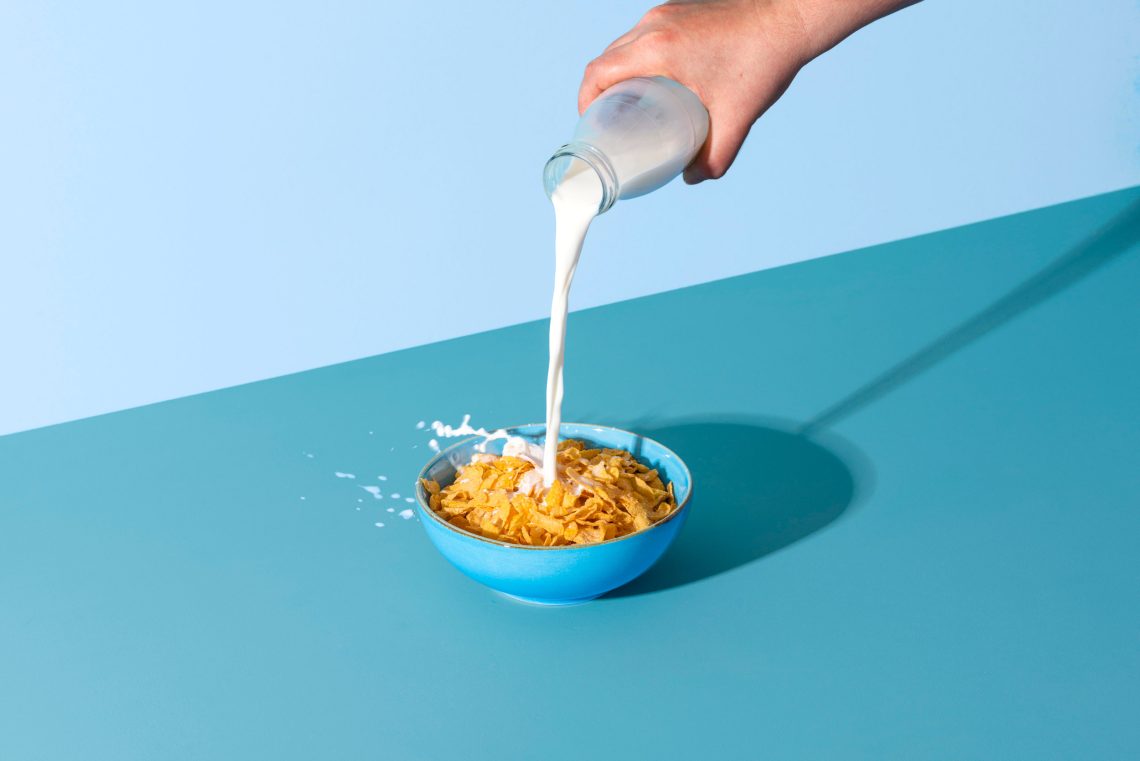 Schüssel mit Cornflakes, in die Milch gegossen wird