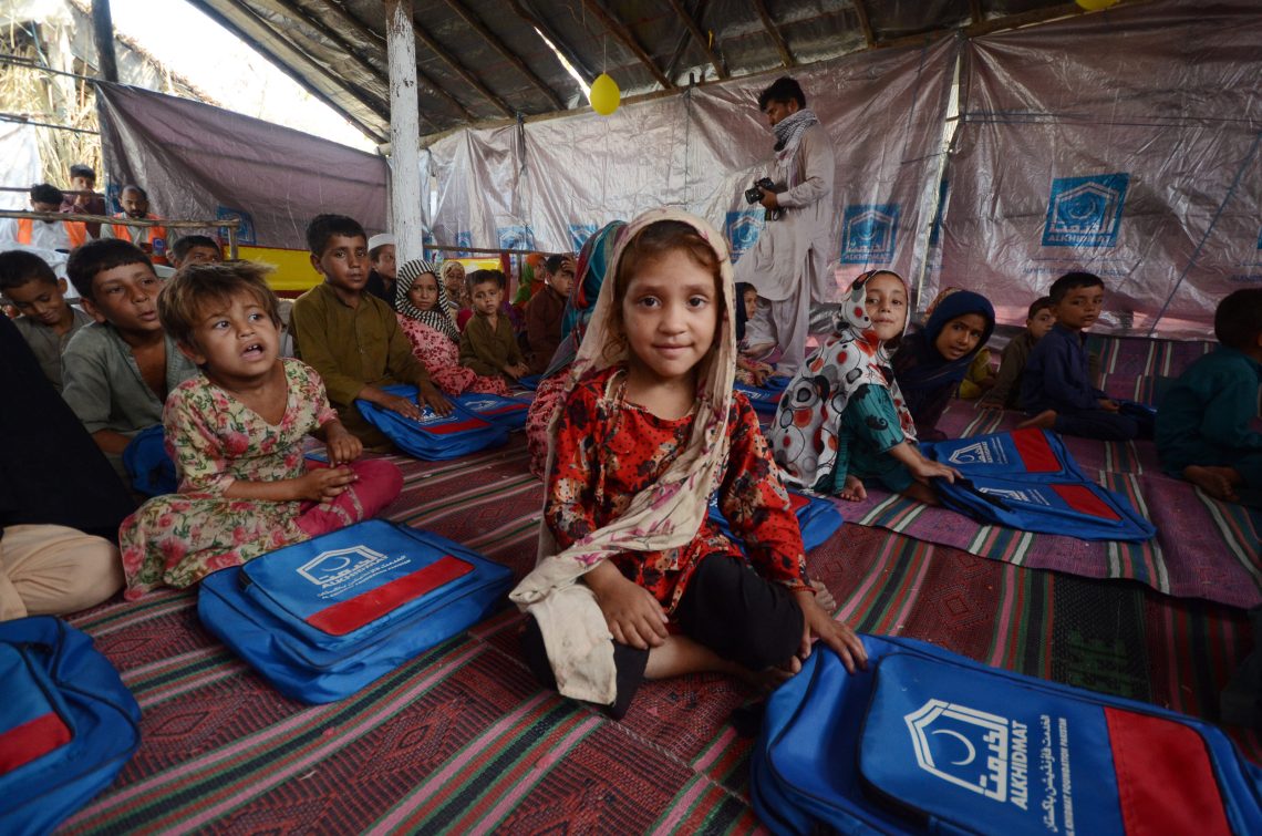 Foto von Kindern die in einem Zelt auf Teppichen sitzen. Ein Mädchen lächelt in die Kamera.