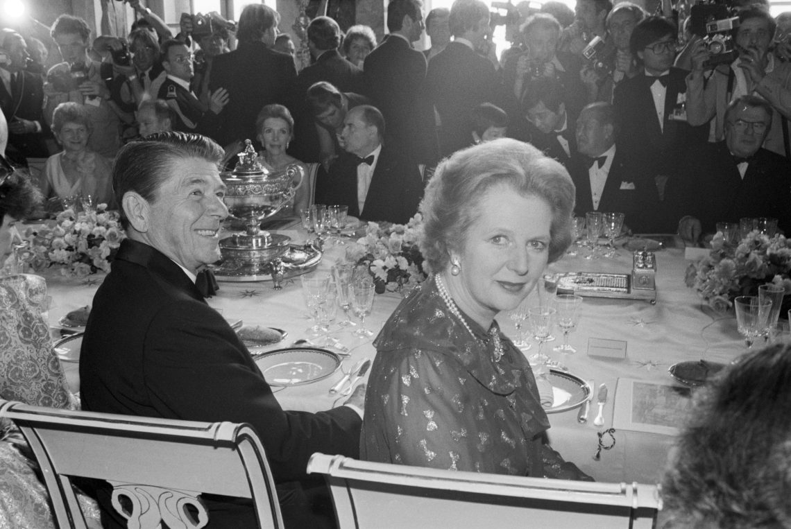 Ronald Reagan und Margaret Thatcher, Vertreter des Neoliberalismus, an einer festlich gedeckten Tafel.