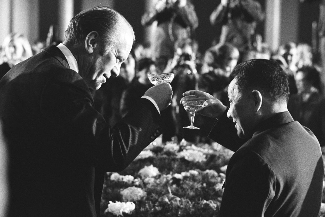 Schwarz-weiß Fotografie von Gerald Ford und Deng Xiaoping, die sich mit Sektschalen anstoßen.