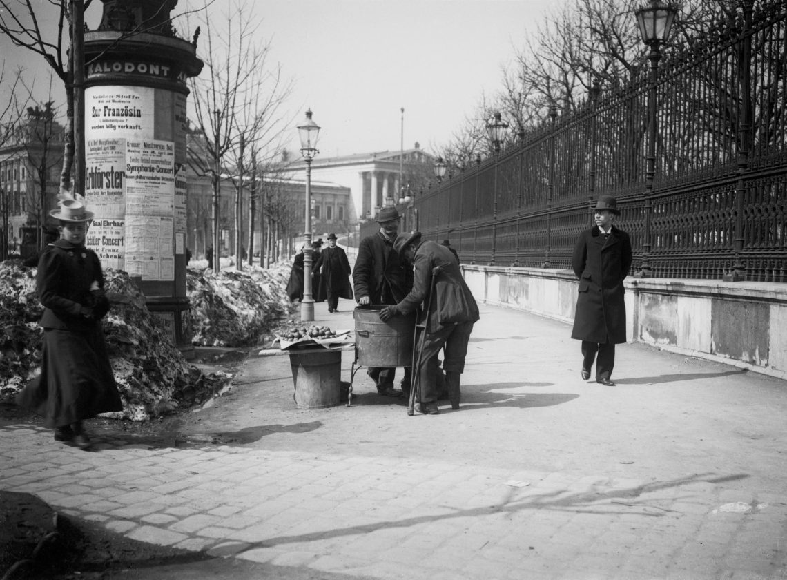 Schwarz-weiß Fotografie des Wiener Rings mit einem Kastanienverkäufer und Spaziergängern.