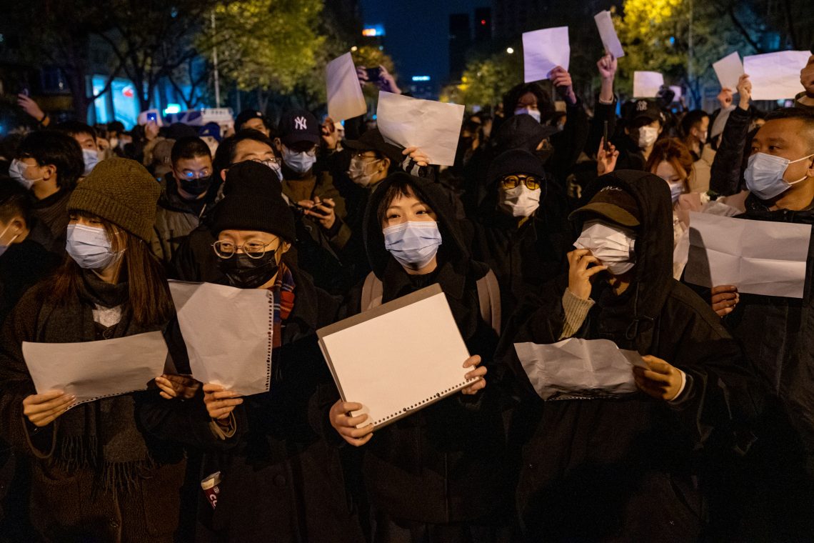 Foto von demonstrierenden Menschen mit Gesichtsmasken, die weiße Zettel ohne Aufschrift in die Höhe halten.