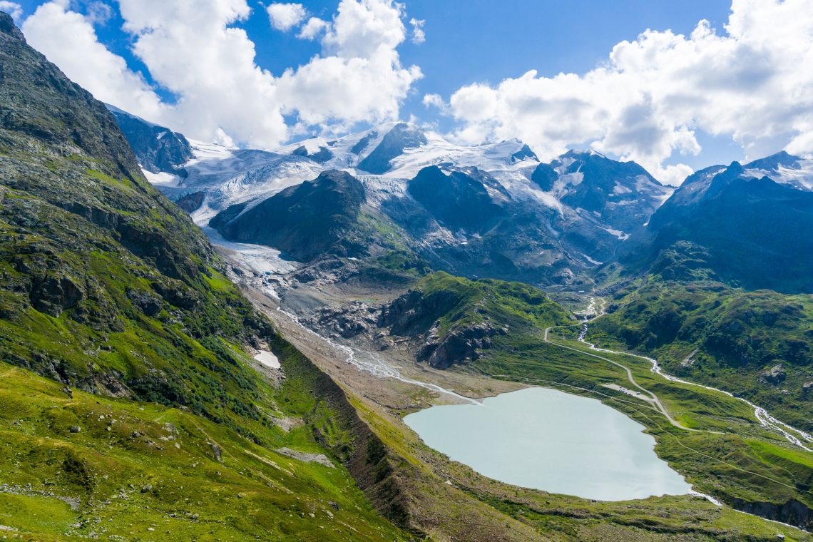 Foto eines Gletschersees in einer Gebirgslandschaft mit Wolken.