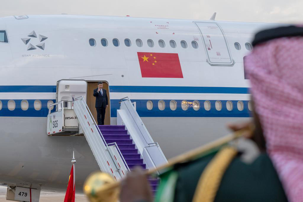 Xi Jinping steht im Ausstieg eines Flugzeugs und winkt. Er wird von Kapelle empfangen. Das Bild soll die Bedeutung der Wirtschaft und des arabischen Raum für China illustrieren.