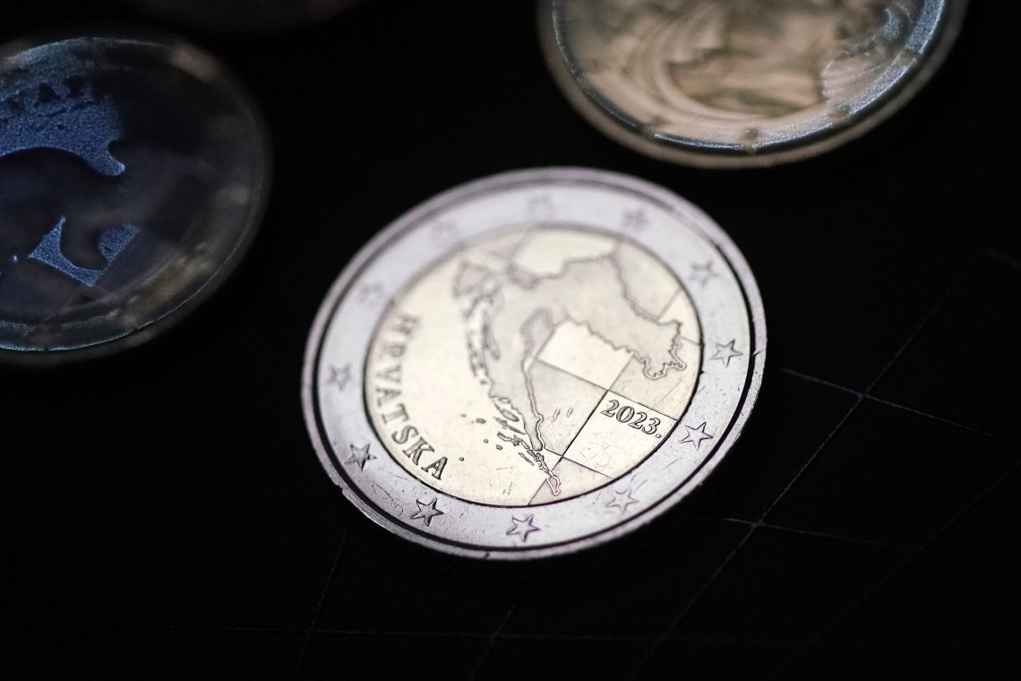Mehrere Zwei-Euro-Münzen vor schwarzem Hintergrund. Auf der Münze ist das Wort Hrvatska für Kroatien und die Kontur des Landes Kroatien zu sehen. Der Euro hat die Prägung 2023.