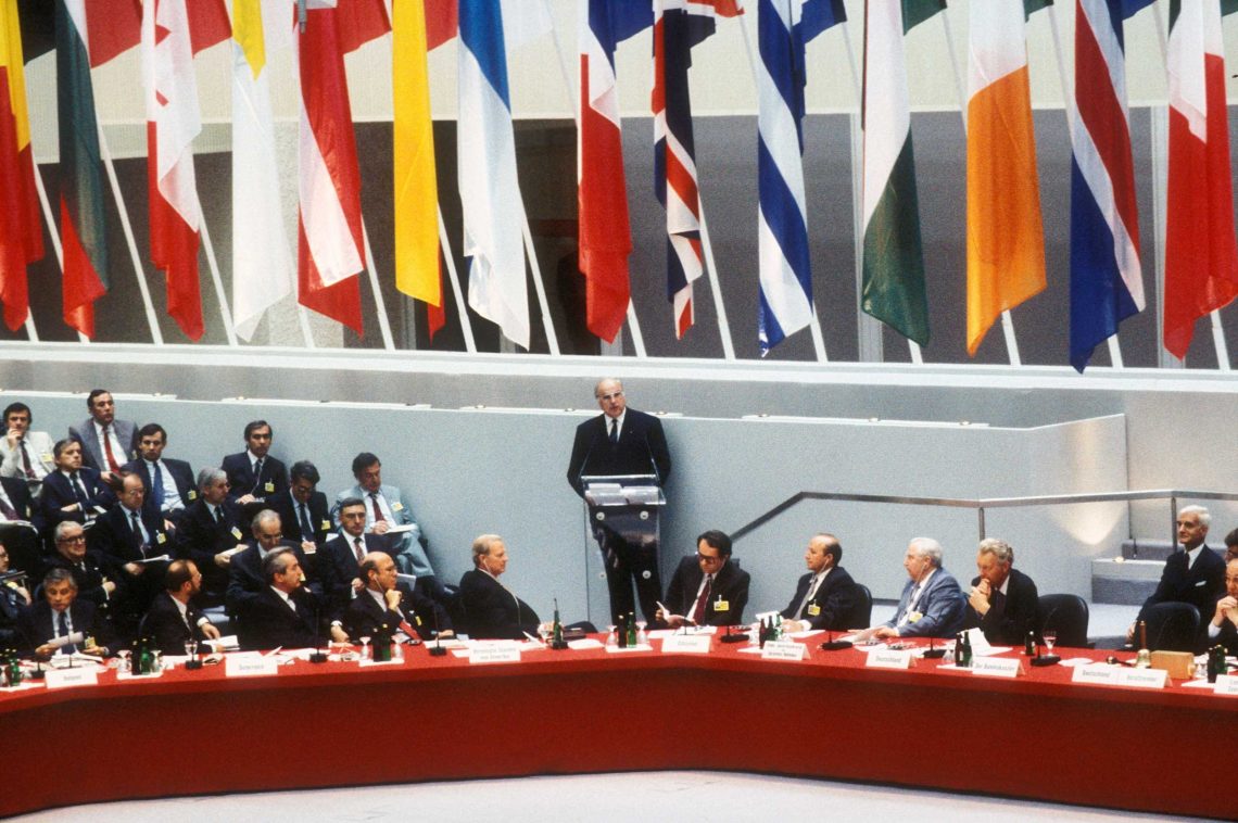 Juni 1991: Außenministern aus 34 Ländern sitzen vor ihren Nationalflaggen bei der 18. Tagung der KSZE in Berlin: Der damalige Bundeskanzler Helmut Kohl steht in der Mitte am Rednerpult im Plenarsaal des Reichstagsgebäudes