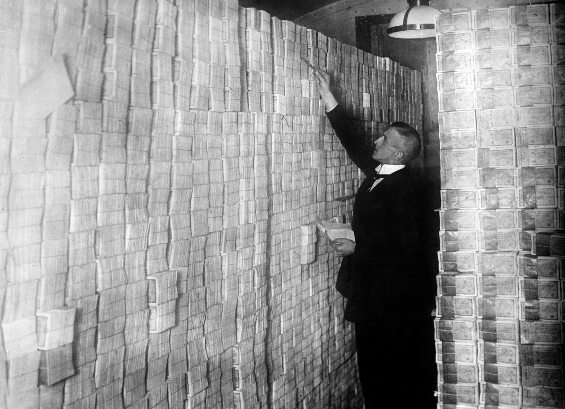 Ein Bankier zählt bis unter die Decke gestapelte Banknoten in Deutschland 1923
