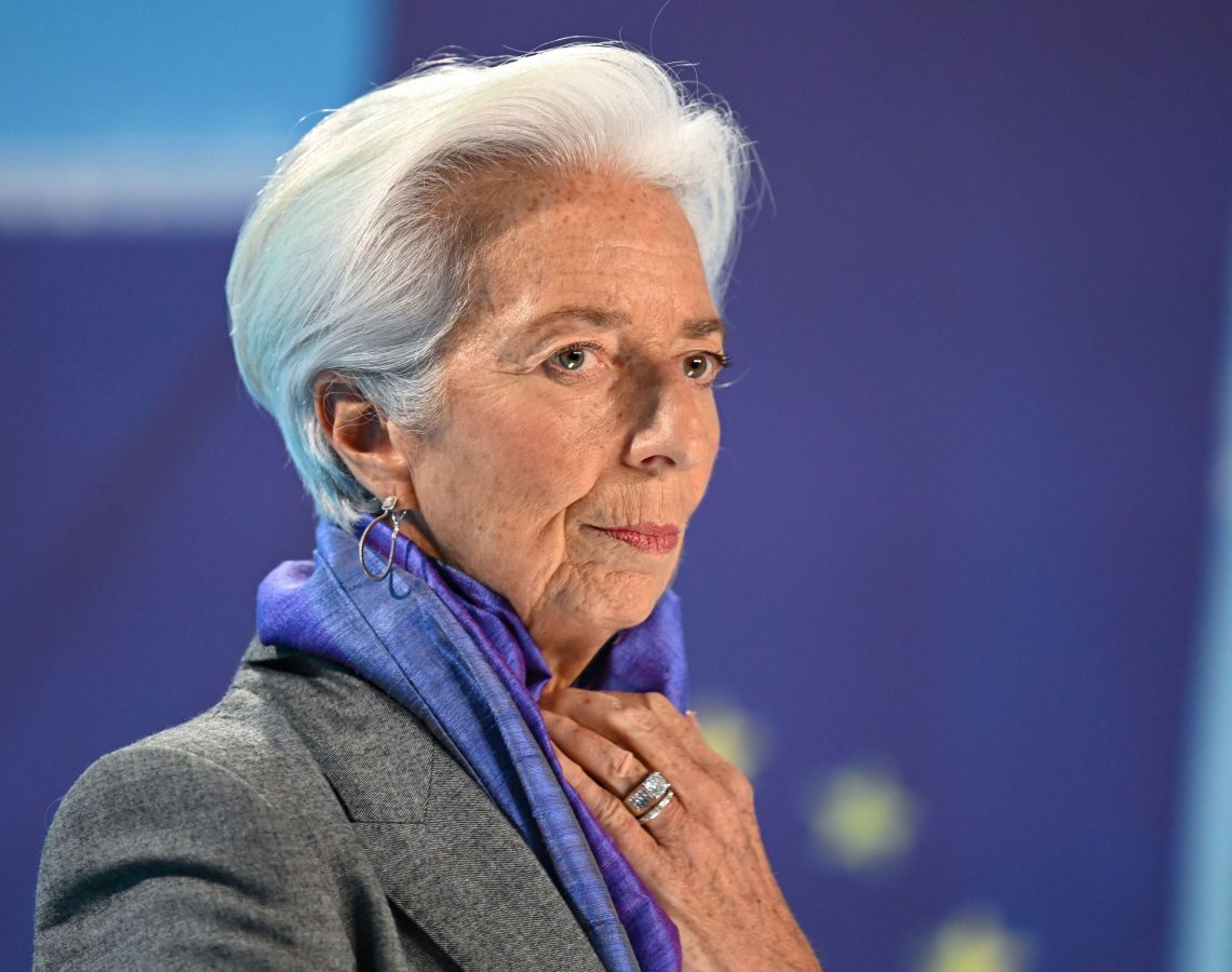 Foto von Christina Lagarde mit blauem Schal und grauem Blazer mit nachdenklichem Gesichtsausdruck. Das Bild ist Teil eines Beitrags über die Rolle von Zinsen während der Inflation.