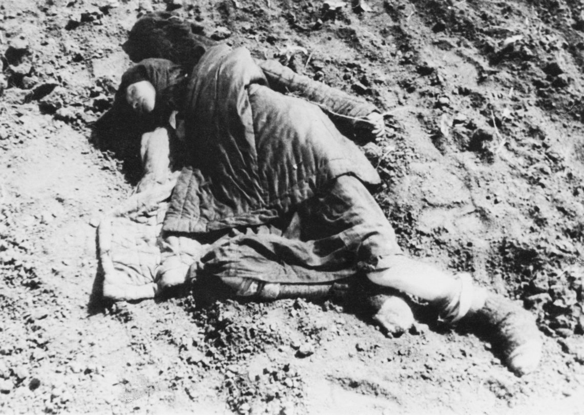 Schwarzweiß Foto des Leichnams einer jungen Frau, die mit einer Decke bedeckt auf der Seite liegt. Die junge Frau ist das Opfer einer Hungersnot. Das Bild gehört zu einem Beitrag über den Holodomor in der Ukraine, dessen Anerkennung als Völkermord oder Genozid noch strittig ist.