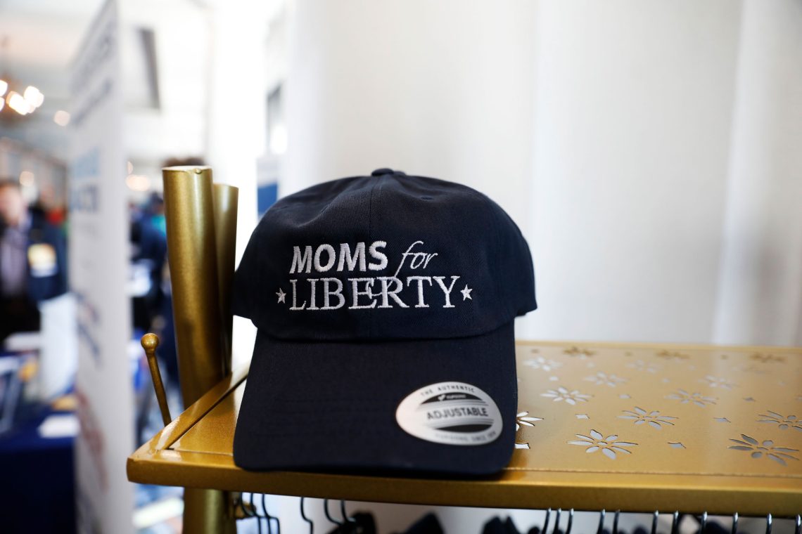 Eine dunkelblaue Baseballkappe mit der Aufschrift „Moms for Liberty“ liegt auf einem Regal. Das Foto ist Teil eines Beitrags über Cancel Culture, die darin als Tugendwahn interpretiert wird.