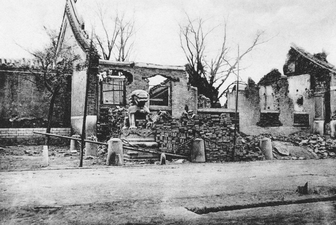 Foto von zerstörten Häusern mit einem Löwen aus Stein.