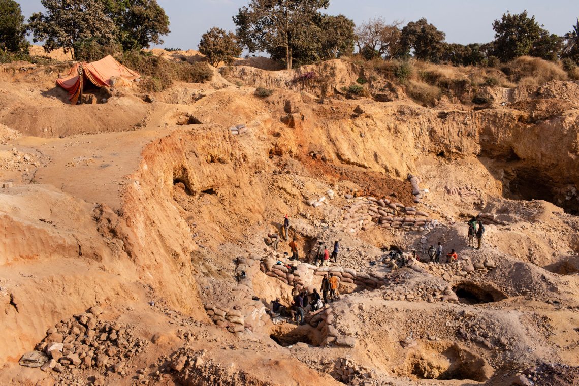 Foto einer offenen Mine mit rostrotem Sand. Unten in der Mine sind Menschen zu sehen. Das Foto ist Teil eines Beitrags über globale Gerechtigkeit und Elektroautos.