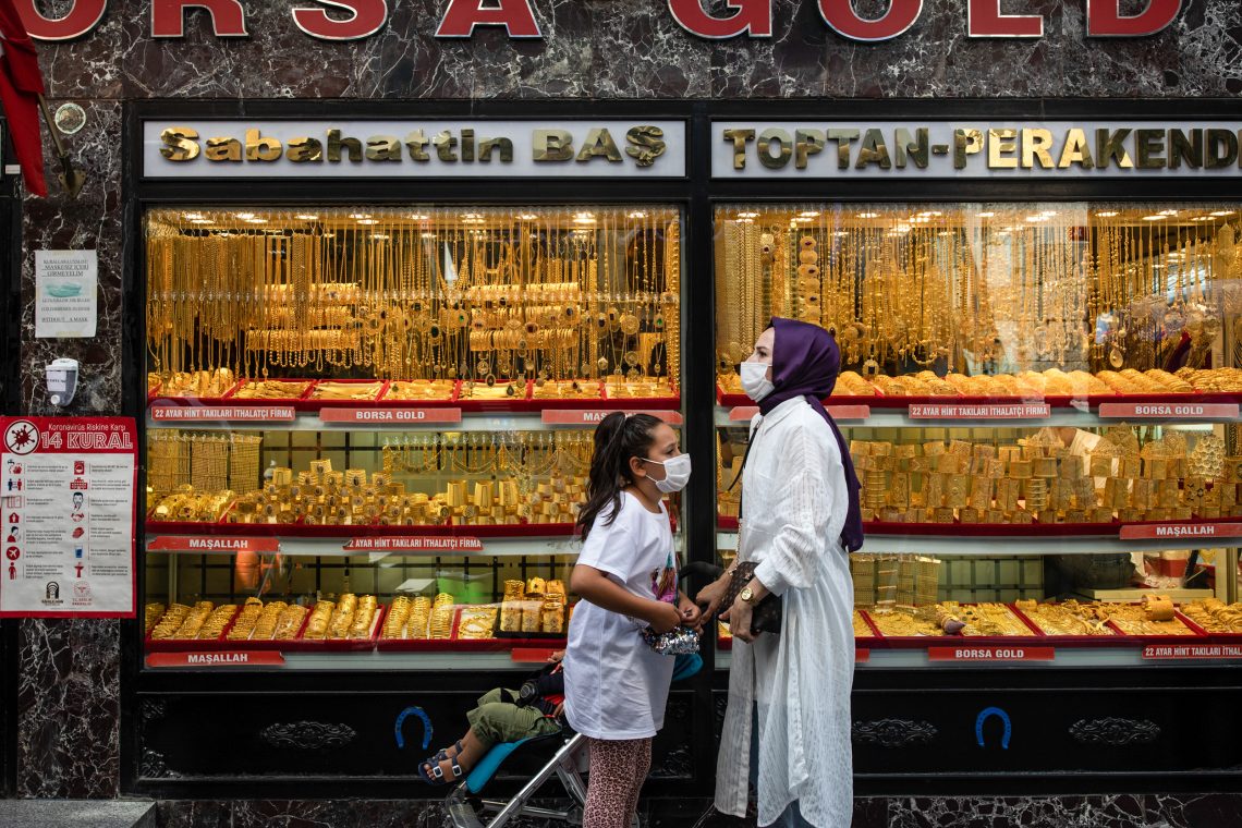 Eine Mutter mit zwei Kindern steht vor einem Juwelier in Istanbul, die Auslage ist voll mit Goldschmuck.