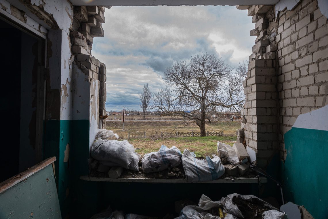 Blick aus dem zerstörten Fenster eines Hauses auf Wiesen und Bäume im Winter. Das Bild illustriert ein Interview über Russland und sein Verhältnis zum Westen.