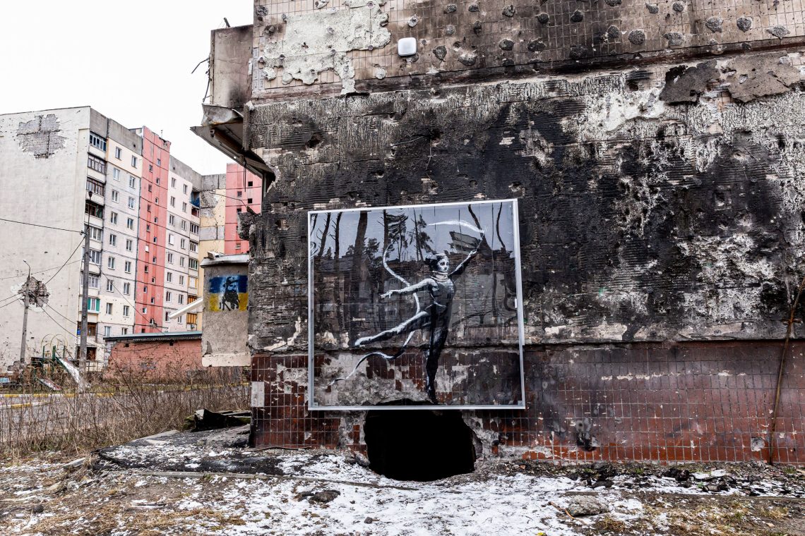 Eine Zeichnung mit einer Taenzerin über einem realen Bombenkrater ist auf einem zerstörten Apartmentgebäude zu sehen. Das Bild illustriert ein Interview mit Velina Tchakarova über die Ukraine und die Sicherheitspolitik der EU.