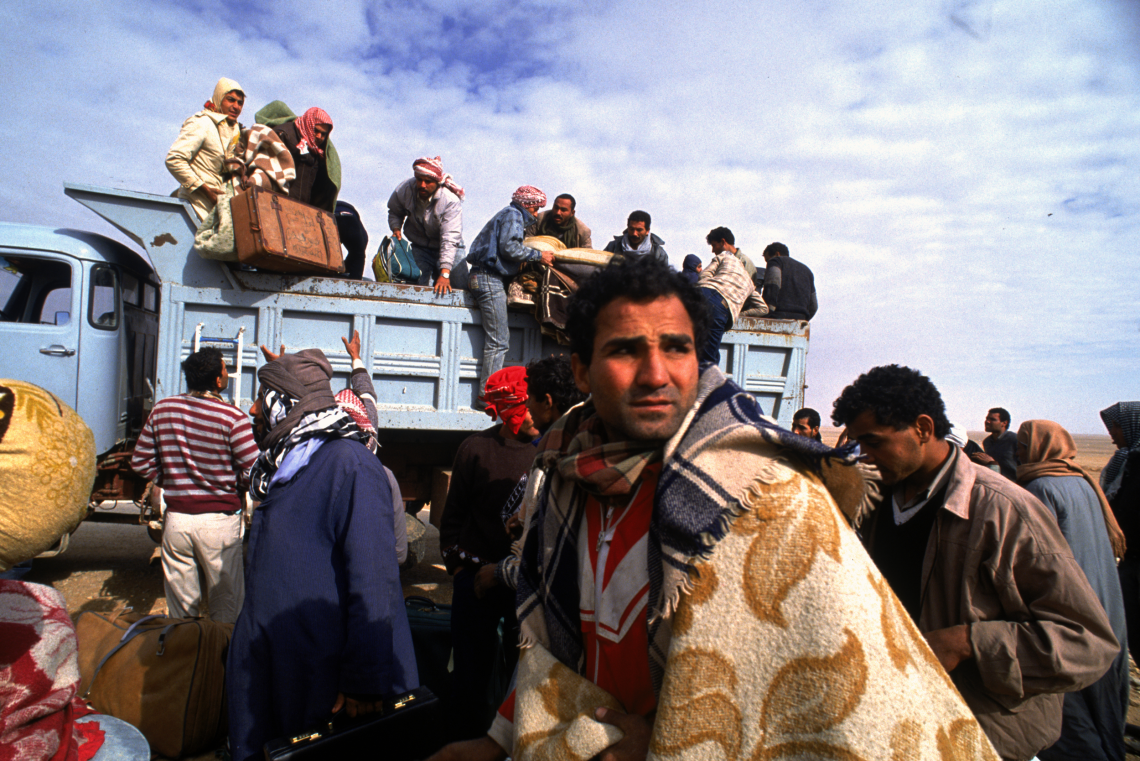 Flüchtlinge mit Decken stehen vor einem Lkw nach Iraks Angriff auf den Nachbarn Kuwait 1990.