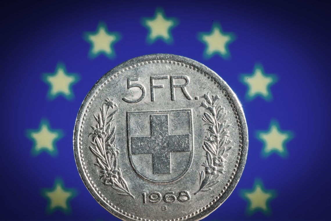 Schweizer Fünf Franken-Münze vor EU-Flagge