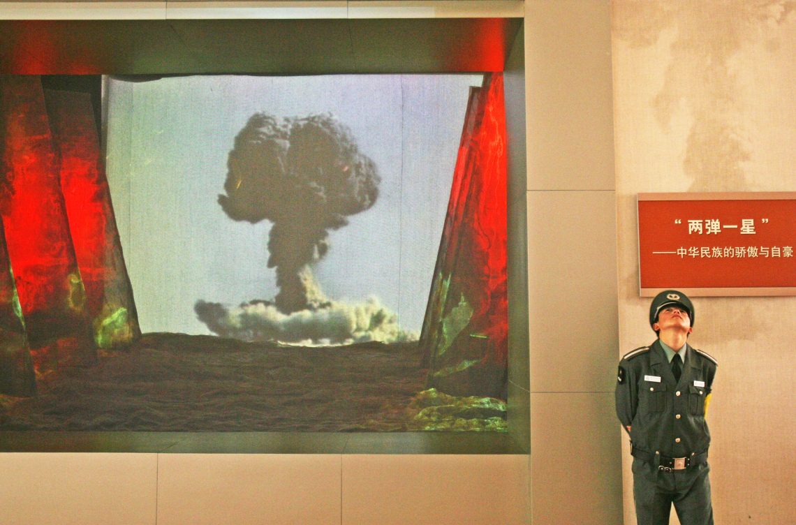 Wachmann in Chinas Militärmuseum neben einem Video zur Atombombe