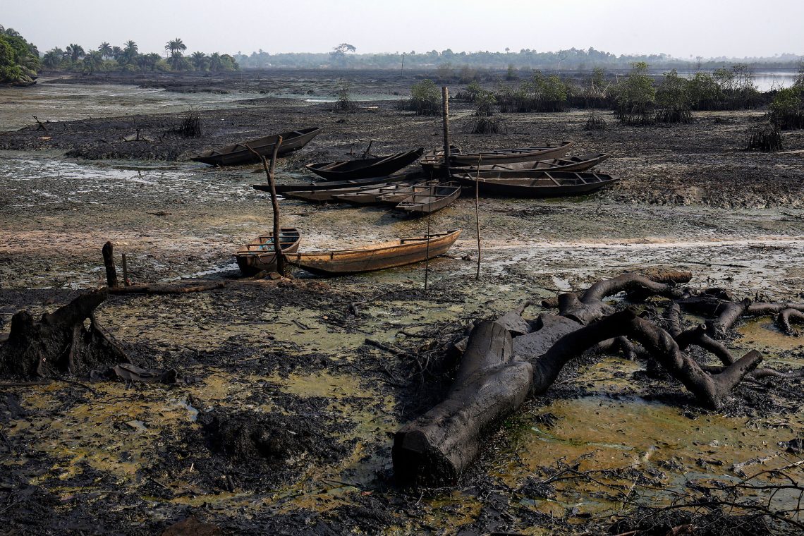 Von Öl beschmutzte Flächen in einem ehemaligen Fluss. Fischerboote liegen verlassen da.