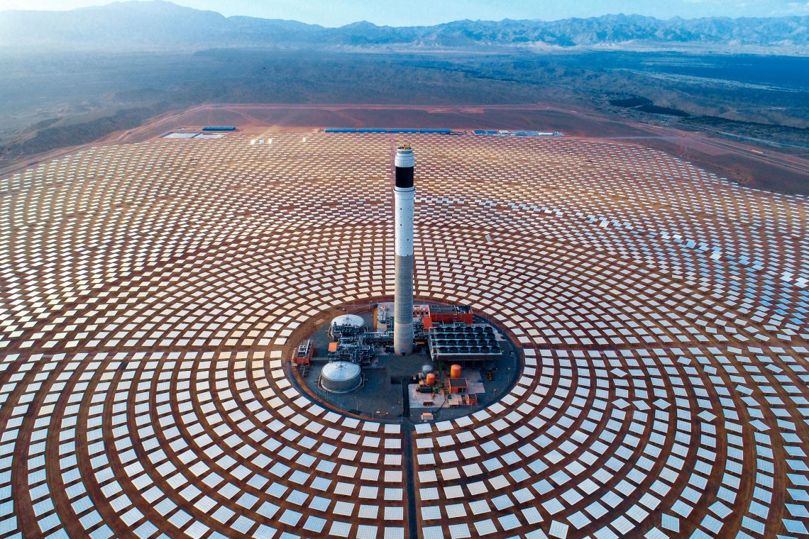Ein Kraftwerk steht inmitten ringförmig angelegter Solarpanele. Das Bild zeigt ein Solartthermie-Kraftwerk in Marokko. Es geht zu einem Beitrag über Energiesicherheit.