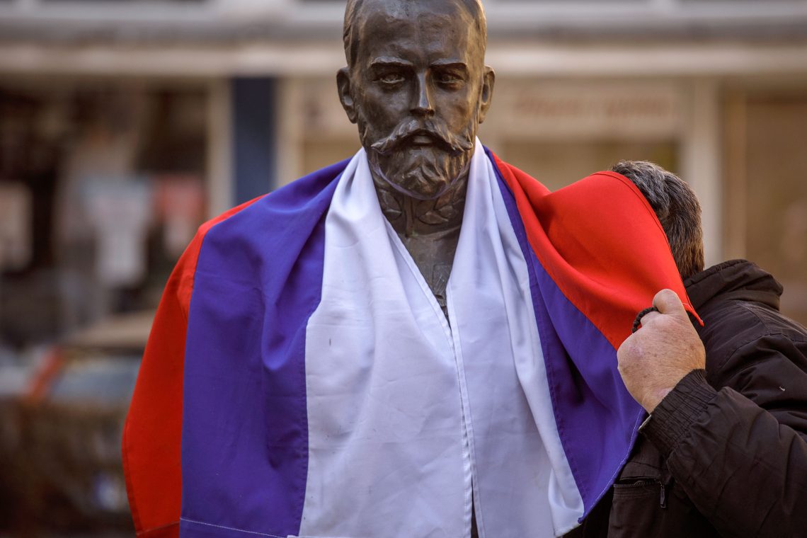 Eine Statue mit einer russischen oder serbischen Fahne verhüllt. Es illustriert einen Beitrag über den Balkan, den Westbalkan und die Beziehungen zu Russland.