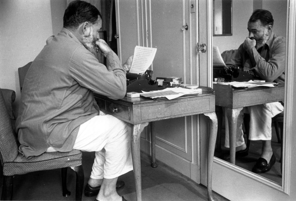 Schwarz-Weiß-Aufnahme von Ernest Hemingway an einer Schreibmaschine aus 1944