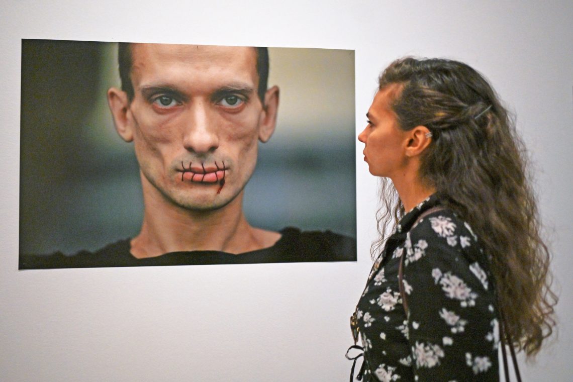 Krakau, 2022: Eine Frau betrachtet ein Foto von Pjotr Pawlenskij, einem russischen politischen Künstler, der sich 2012 den Mund zunähte, um seine Solidarität mit den Frauen der Band Pussy Riot zu bekunden.