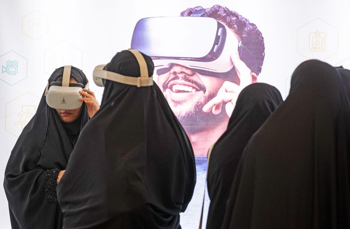Teheran, April 2023: Zwei Frauen sehen sich während ihres Besuchs der Internationalen Koranmesse simulierte 3D-Filme von der Pilgerstadt Karbala und von Imam Hussein, einem Enkel des Propheten Mohammed, der im 7. Jahrhundert gelebt hat, an.