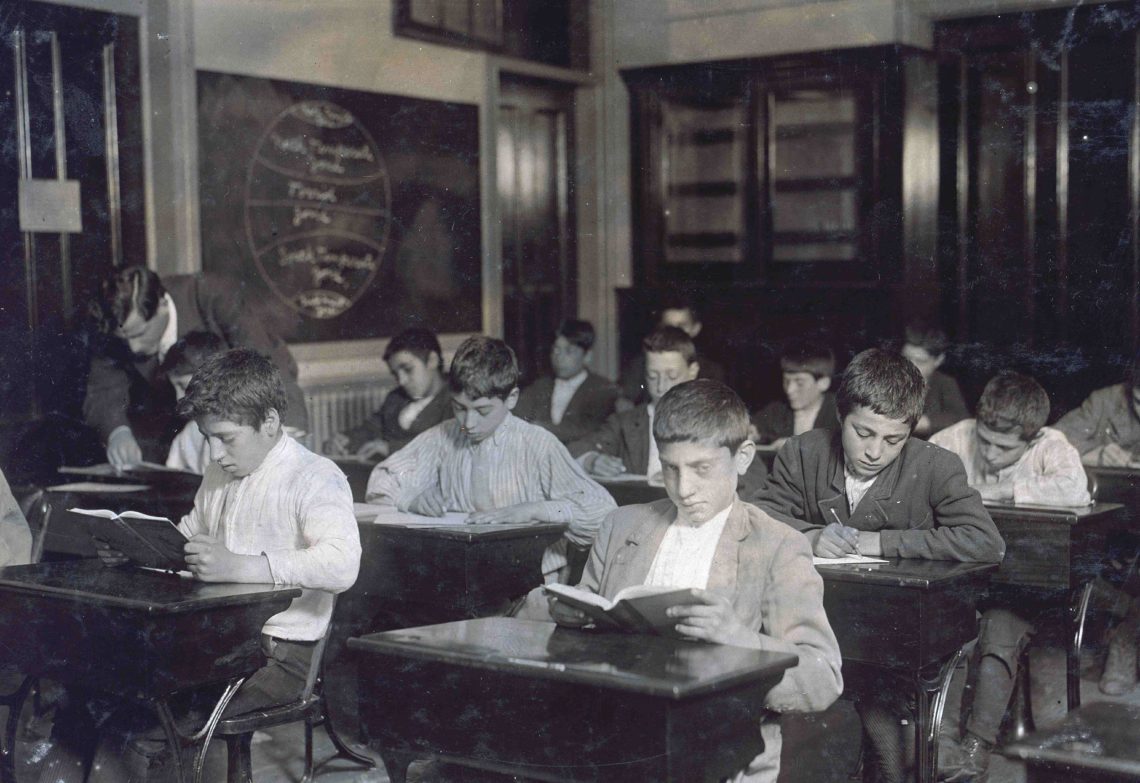 Schüler sitzen in einem Klassenzimmer und lernen. Das Bild illustriert einen Beitrag über Arbeitsmigration und Zuwanderung.