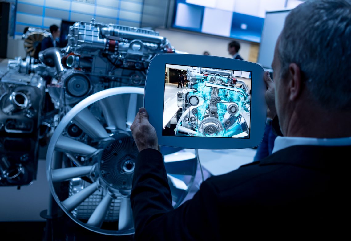 Ein Besucher der Automesse in Hanover betrachtet einen Dieselmotor auf seinem Tablet, auf dem das Innenleben der Maschine angezeigt wird.