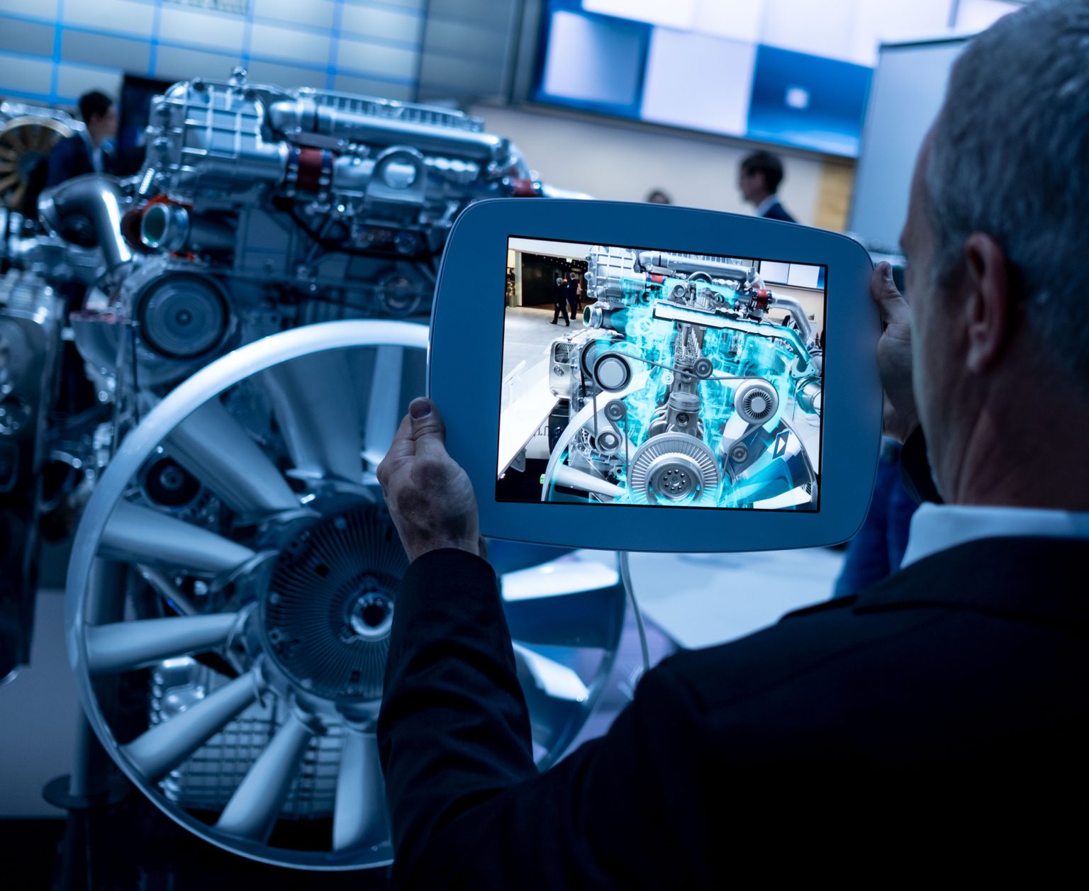 Ein Besucher der Automesse in Hanover betrachtet einen Dieselmotor auf seinem Tablet, auf dem das Innenleben der Maschine angezeigt wird.