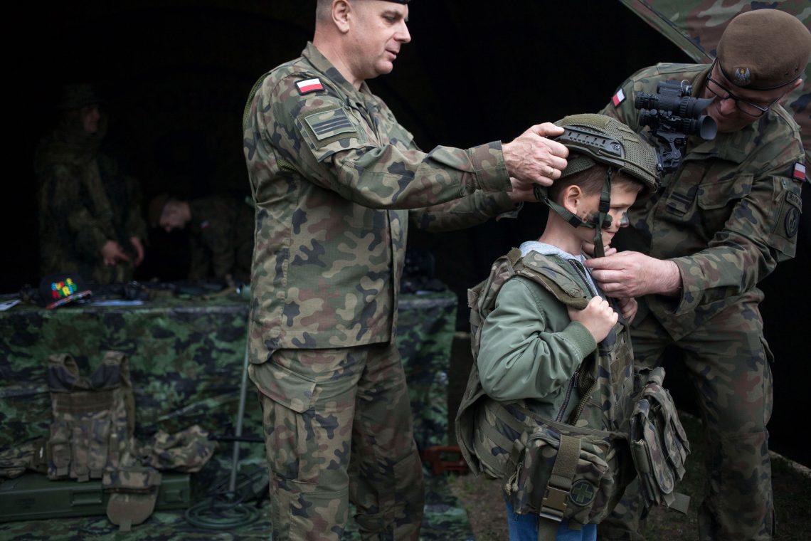 Polen, 2022: Soldaten helfen einem Kind beim Anziehen einer Militäruniform während des Rekrutierungspicknicks für den neuen freiwilligen allgemeinen Wehrdienst in Kozienice.