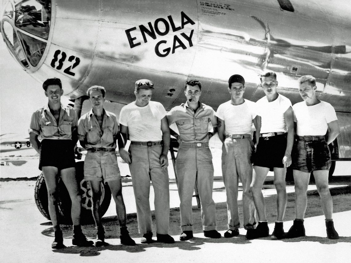Sechs Männer posieren, teilweise in kurzen Hosen und T-Shirts, vor einem Bombenflugzeug mit der Aufschrift 82 und Enola Gay. Das Bild ist Teil eines Beitrags über Frage, ob die Abwürfe der Atombomben auf Hirshima und Nagasaki Kriegsverbrechen waren oder nicht.